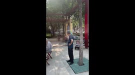 Passing mascot frog dances while elderly folk music band plays music