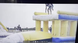 Get ready for a splash! Watch as this daring adventurer takes a leap from a giant water inflatable, only to go for an epic tumble into the water.