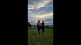 Girl's unexpected fall while posing on a wooden log with a scenic background