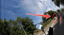 Close call: in a sharp turn, a scooter slips on the road towards an oncoming car but manages to rebalance just in time. Paris suburb, Route de Versailles, Rocquencourt. 28 july 2024