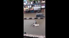 Stricken resident rides a mattress through flooded road in Delhi