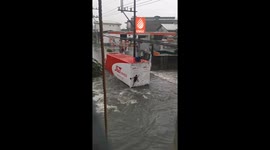 Local clings to back of delivery truck to avoid raging typhoon floods
