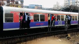 Commuters risk their lives clinging from open doors of packed train in Mumbai