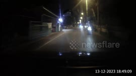 A blind corner overtake on a narrow road at night time almost causes a head-on collision. The driver brakes hard and sounds the horn.