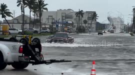 Vehicles struggle to pass through submerged streets as Storm Debby hits Florida