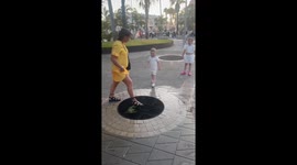 Children playfully splashed by water jets in Playa de las Américas, Spain