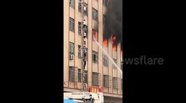 Workers climb down ladder to escape burning factory building in southern China