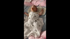 Adorable Chinese newborn twists into sleep in his crib