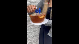 Girl hands clueless dad a birthday cake with a firecracker hidden as a candle