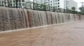 Waterfall cascades onto road during heavy rain in Thailand