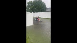 Father and son row boat through flooded road in Longs, South Carolina