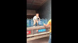 Young boy helps father with water delivery in China