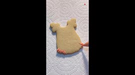 Girl makes a cute daisy baby onesie sugar cookie for a baby shower