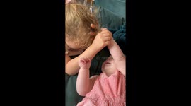 Watch as big sister handles baby brother’s hair-pulling with cool grace