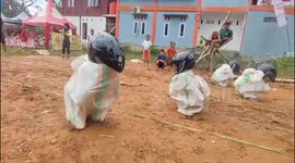 The excitement of the sack racing game using helmets which is very funny in Indonesia