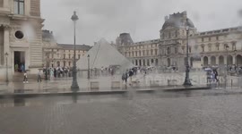 Louvre Museum Pyramide under rain (moving bus view). Paris, France. 17 aug 2024