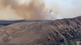 Wildfire flames spread up hillside