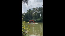 Excavator rows across water using arm as propulsion in Kottayam, India
