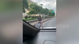 Tourist rides electric suitcase along ROAD to airport in Thailand