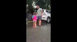 Family laughter: Daughter soaks dad with hose while he cleans the car