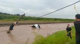 Mum and daughter cling to utility pole after their car was swept into raging river in China