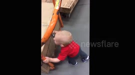 Baby 'Hercules' pushes garden furniture set around warehouse