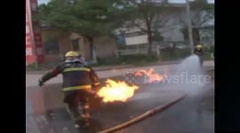 Firefighter carries on fire gas cylinder out of house