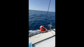 Man Dangles by Rope From Moving Boat
