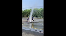 Firemen play skipping rope with their water hose