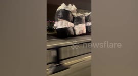 Overloaded tricycle pulls dozens of huge bags of rubbish along road