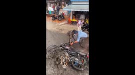Motorcycle held by people to prevent flood sweep in Hyderabad