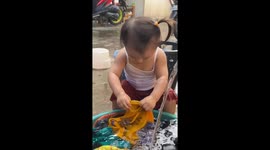 Toddler washes clothes by hand to help family