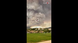 Helicopter hovers near towering smoke column as wildfire ravages Santa Ana Mountains