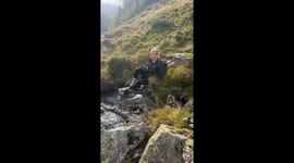 Girl falls after attempting to slide down wet rock on hike