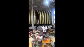 Restaurant staff cling to awnings being blown by strong wind