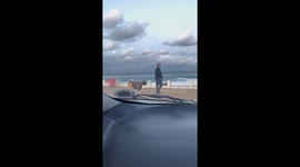 Man Walks His Sheep at the Beach