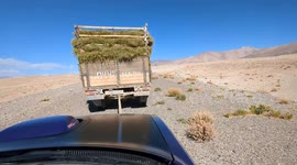 An old Soviet farm truck towing a modern American V8 muscle car in the Tajikistan mountains