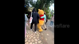 迪士尼维尼熊玩偶被游客拍打头部后摔倒
