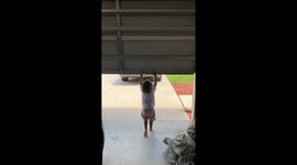 Little Boy Hangs on to Opening Garage Door