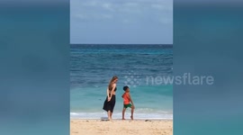 Cheeky kid shows beachgoer how to pose for selfies