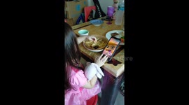 A lovely girl eating French fries and watching cartoons on the phone.