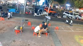 Wind blows chairs and tables as two men eat noodles