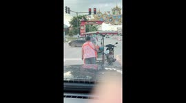 Food vendor grills pork while she waits for lights to change
