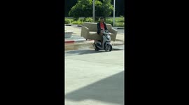 Worker causes hilarity by sitting on sofa being carried on motorcycle