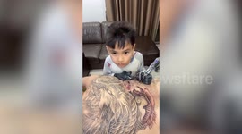 Boy tattoos complex designs on man's back in his pyjamas