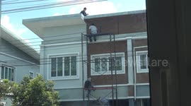 Workmen on scaffolding without any safety gear work on repairs to a house.