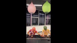 Two friends compete in bottle-toss game with water balloons