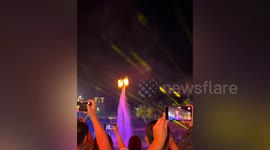 Performer holding fire pots flies on water jet pack