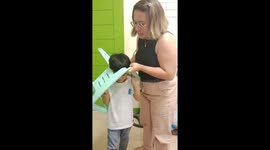 Teacher tends to schoolboy with head stuck in plastic chair