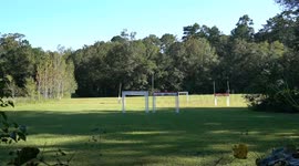 One small drone quickly races through a drone race course in a field